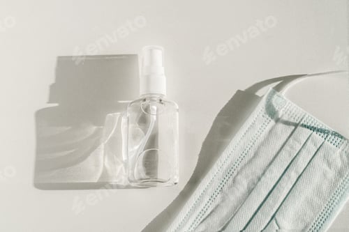 Preview: The antiseptic and mask lying down on the surface on a white background.