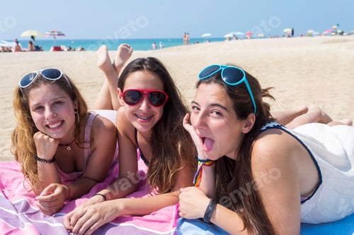 Preview: smiling girls best friends lying on beach while looking camera