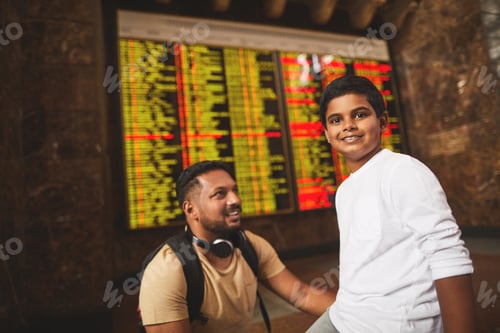 Preview: Cheerful Nice Little Boy Smiling While Standing With His Father Near The Departure Board