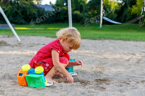 Preview: Little girl playing with sand and toys at playground in park. Small child outdoors in summer