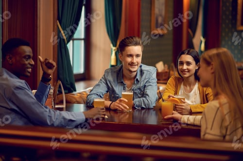 Preview: Cheerful friends clink glasses at counter in bar
