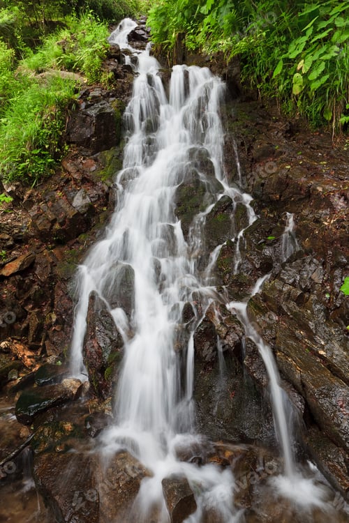 Preview: Waterfall Flowing Down Rocky Surface With Greenery