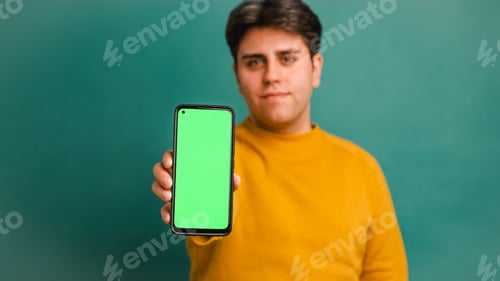 Preview: Happy doctor showing mobile phone with green screen