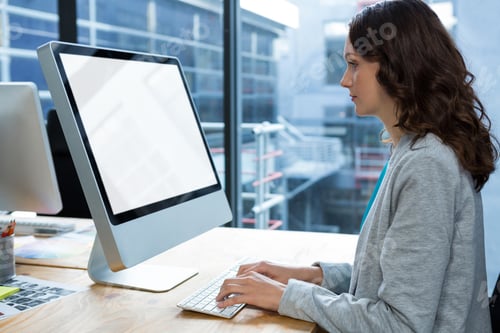 Preview: Female graphic designer working over computer at desk