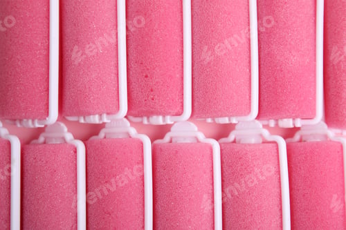 Preview: Many pink hair curlers as background, top view