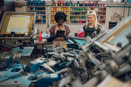 Preview: Interracial supervisor with tablet monitoring print shop worker with plate
