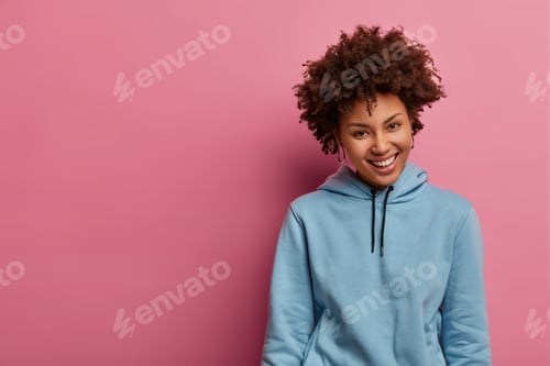Preview: Charming glad Afro American woman laughs positively, looks cheerfully at something pleasant, wears c