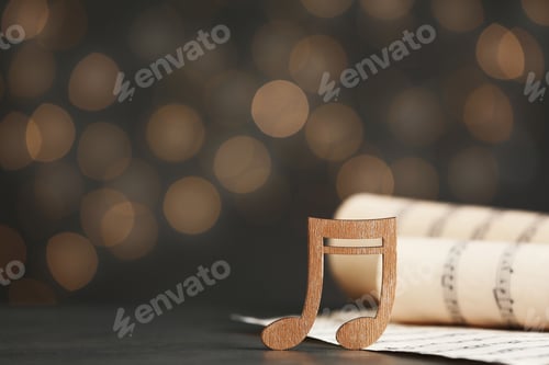 Preview: Music note and sheets on table against blurred lights, space for text. Bokeh effect