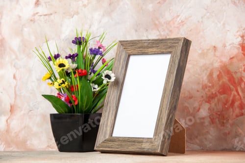 Preview: Side view of dark brown empty wooden photo frame and beautiful flower pot on mixed colors background