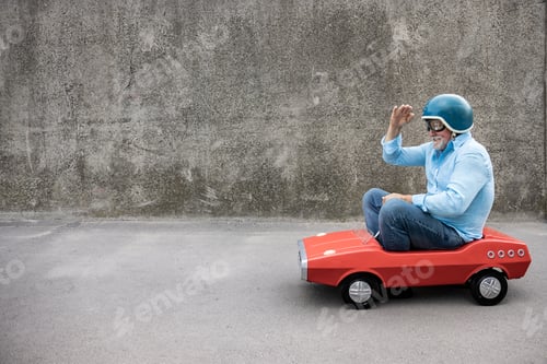 Preview: Funny businessman driving retro pedal car outdoor
