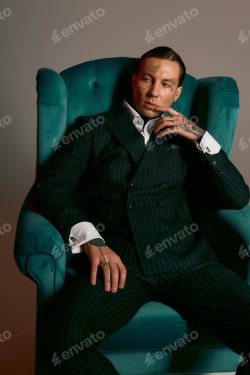 Preview: Stylish young man poses elegantly in a chic armchair with confident charm and poise