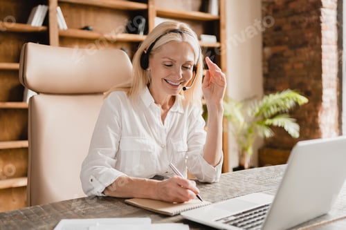 Preview: IT support agent, secretary wearing headset taking notes while talking helping clients using laptop