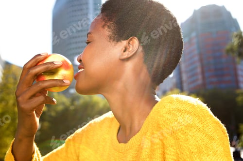 Preview: Close up portrait of healthy young black woman with apple outdoors