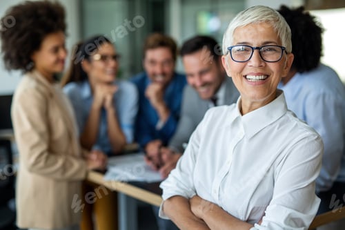 Preview: Confident stylish european mature business woman standing at workplace