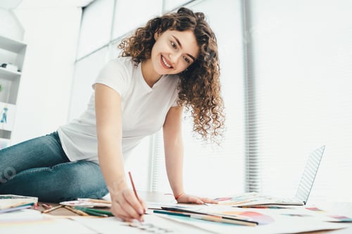 Preview: The woman sitting on the table and drawing on a paper.