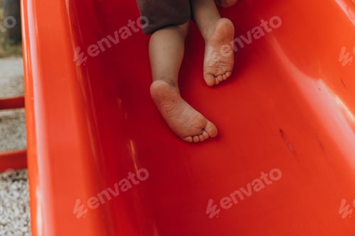 Preview: barefoot child climbs a slide in the playground