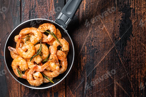 Preview: Fried with butter and garlic prawns shrimps in a skillet. Wooden background. Top view. Copy space