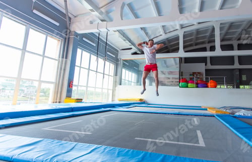 Preview: Fitness, fun, leisure and sport activity concept - Handsome happy man jumping on a trampoline