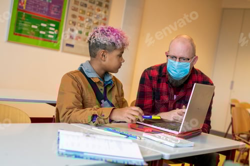 Preview: Young teenage students working from their laptop with help from their teacher
