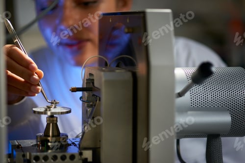Preview: Scientists placing object on scientific equipment using tweezers