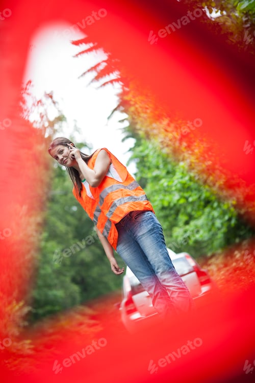Preview: Young female driver wearing a high visibility vest, calling the