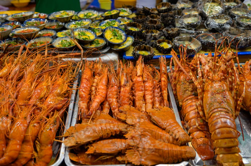 Preview: High angle heaps of spiny lobsters placed in containers on stall in local market in Vietnam