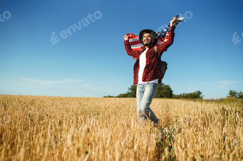 Preview: 4th of July. American Flag. Traveler with the flag of America. man in hat, backpack, shirt and jeans