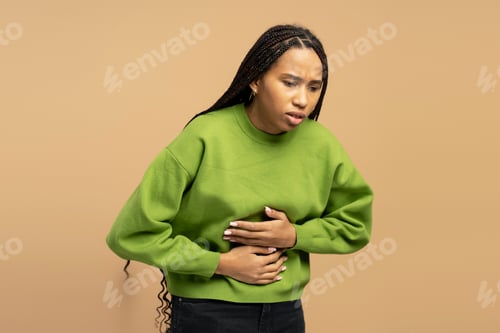 Preview: Sad African American woman suffering from strong stomach ache on beige background