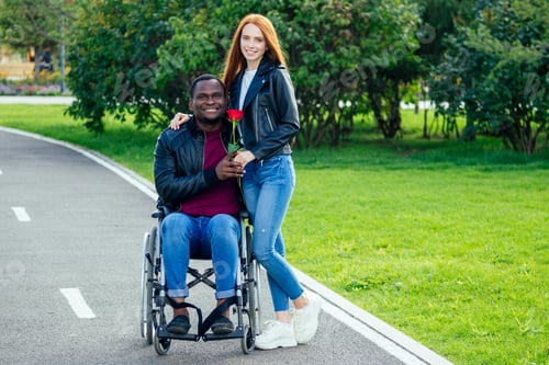 Preview: afro american man sitting on wheelchair ,his redhaired ginger girlfriend