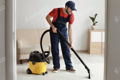 Preview: Male worker cleaning carpet with vacuum in living room