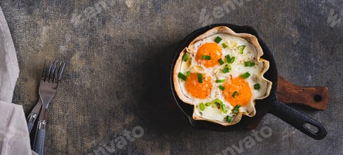 Preview: Fried eggs with green onions in a tortilla on a frying pan on the table top view web banner