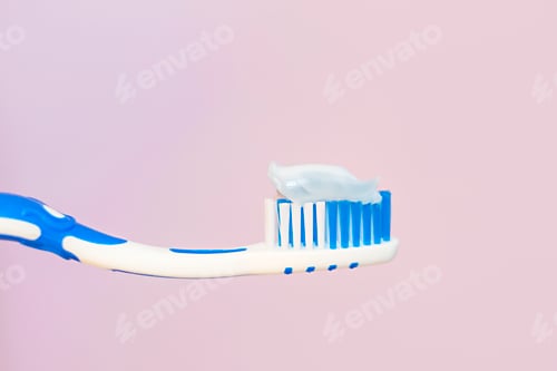 Preview: Toothbrush with white toothpaste close-up on pink background.