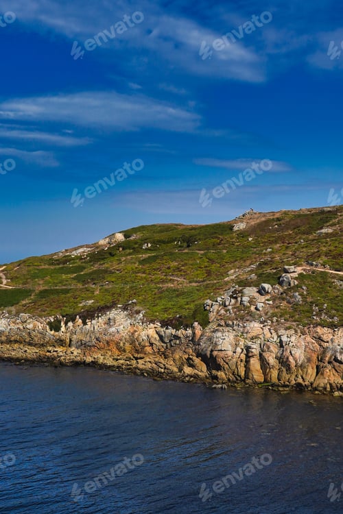 Preview: Vertical shot of a mountain in front of the water in La Coruna, Spain