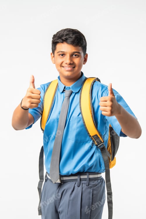 Preview: Indian Asian school boy in uniform with giving thumbs up, celebrating success or pointing to blank