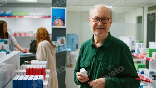 Preview: Elderly client smiling and looking at cardiology pills box in pharmacy