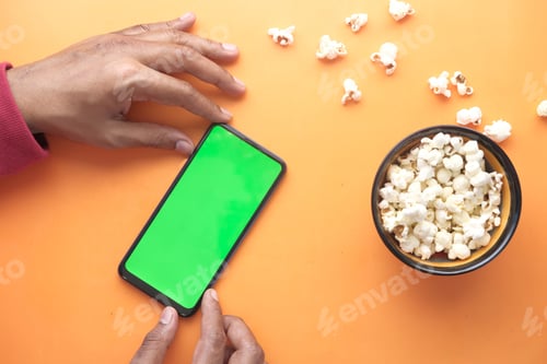 Preview: man hand using smart phone and eating popcorn