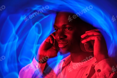 Preview: Smiling black man in headphones in neon illumination