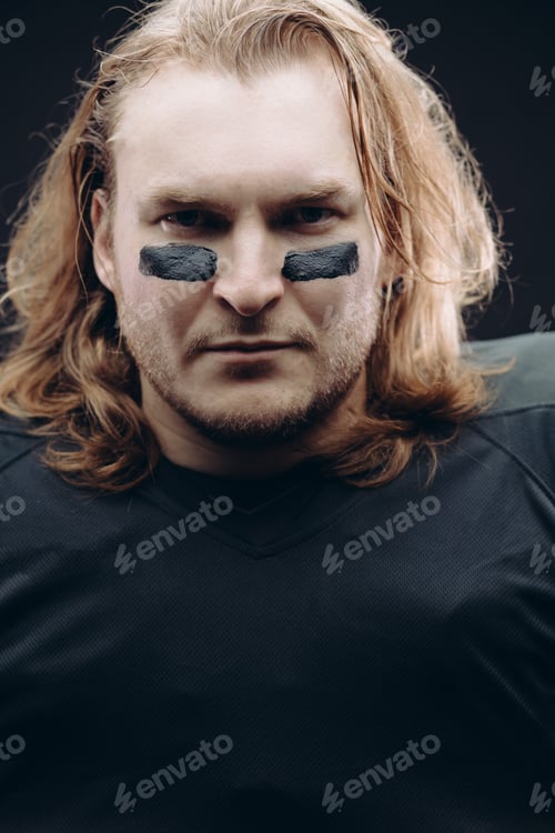 Preview: Determined American football player posing with painted face and chewing gum