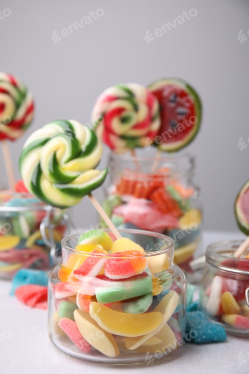 Preview: Tasty different candies in jars on light grey table