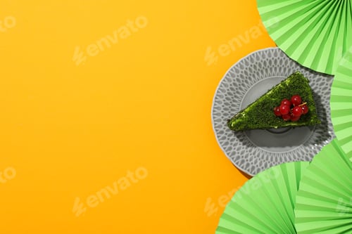 Preview: Piece of spinach cake on plate and paper decorations on yellow background, space for text