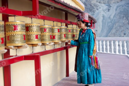 Preview: Two Indian women in traditional Leh attire spin golden prayer wheels at a monastery