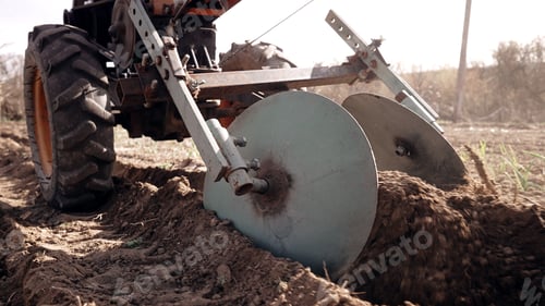 Preview: Farmer man works, ploughing in garden chernozem field with motorized unit motoblock - type of small
