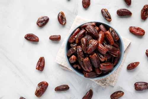 Preview: Pitted Organic Dates in Bowl on gray background, top view. Flat lay, overhead, from above.