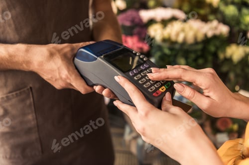 Preview: cropped image of customer paying with credit card at flower shop and entering pin code