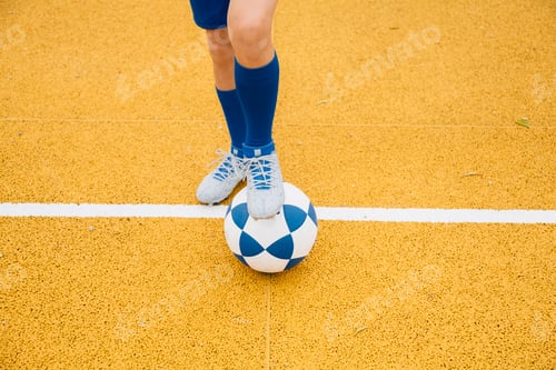Preview: Little unrecognizable boy playing soccer of yellow background