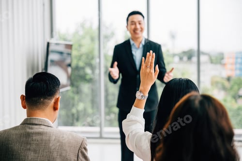 Preview: Businesspeople in seminar meeting room raise their hands to engage the speaker, reflecting active