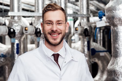 Preview: cheerful engineer in glasses and white coat looking at camera
