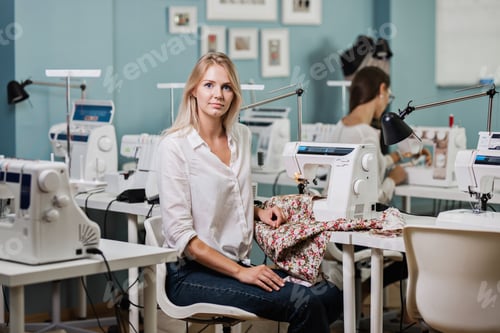 Preview: A smart-looking pretty blond woman wearing white shirt is sewing with the electric sewing-machine
