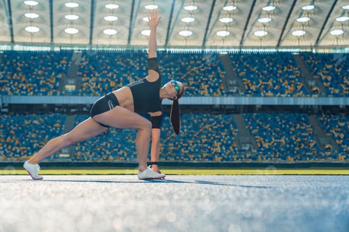 Preview: Young female runner stretching arms and legs before running