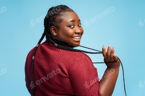 Preview: Beautiful African American woman with stylish braids looking at camera isolated on blue background